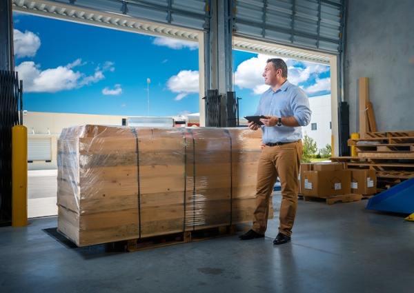 Someone comparing a pallet of freight against its documentation 