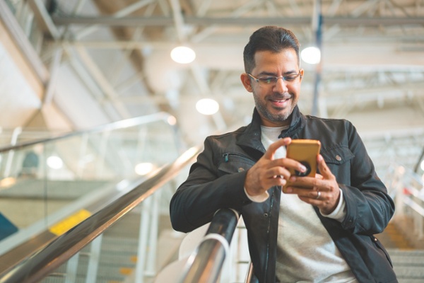 man browsing his phone on an escalator