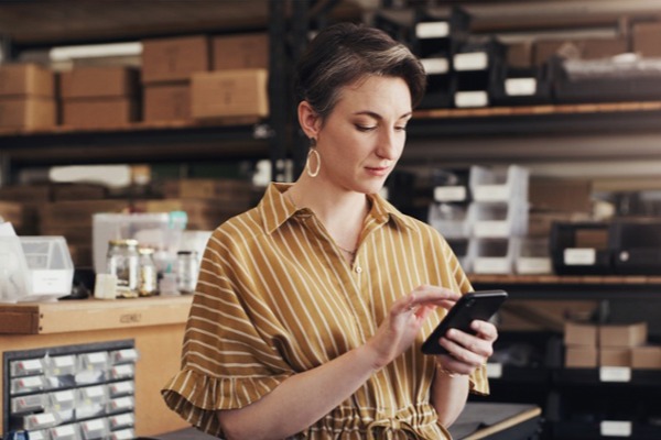 woman managing inventory on a phone in a warehouse